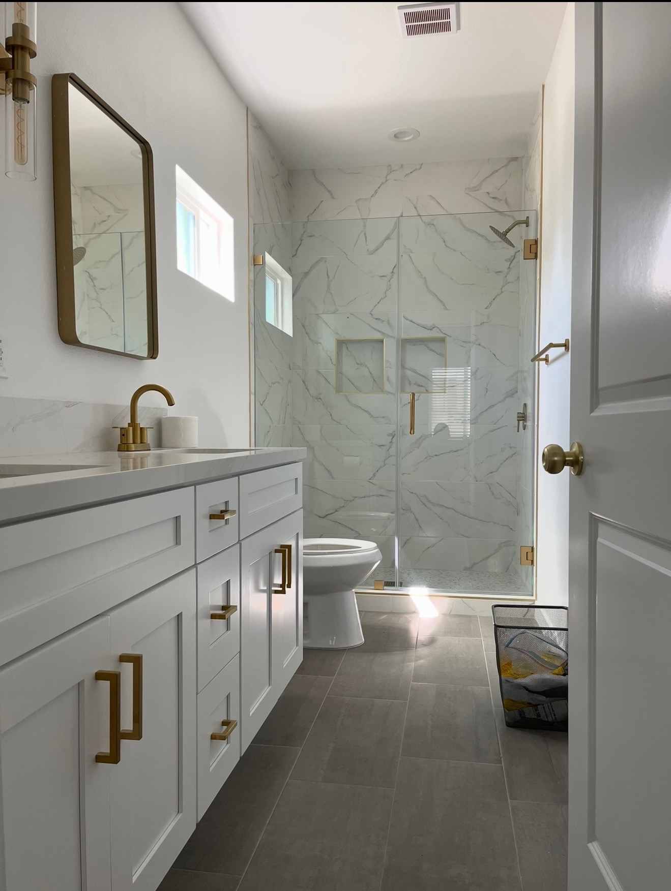 Bathroom with a tiled shower, glass enclosure and gold fixtures from the Campos Contractors project gallery